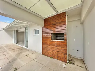 Vista externa de uma área coberta com piso de concreto e parede de madeira em Lajeado.