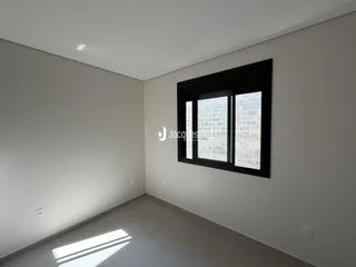 Foto de um cômodo interno com paredes brancas e uma grande janela preta.