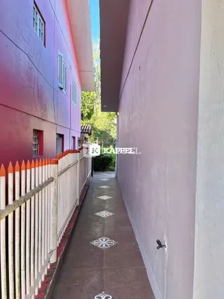 Uma foto de um corredor externo com paredes coloridas e um caminho pavimentado.