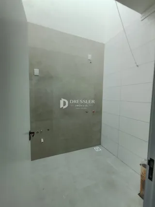 Vista interna de um ambiente com paredes brancas e piso claro.