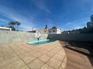 Vista externa de uma área de lazer com piscina e piso de cerâmica em Lajeado.