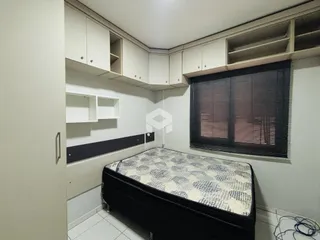 Quarto com armários brancos e janela com persiana escura.