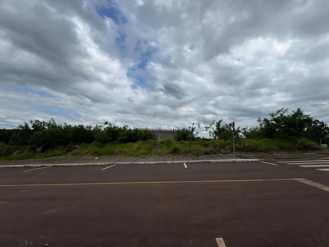 Uma vista externa mostrando uma área pavimentada e vegetação ao fundo da propriedade.