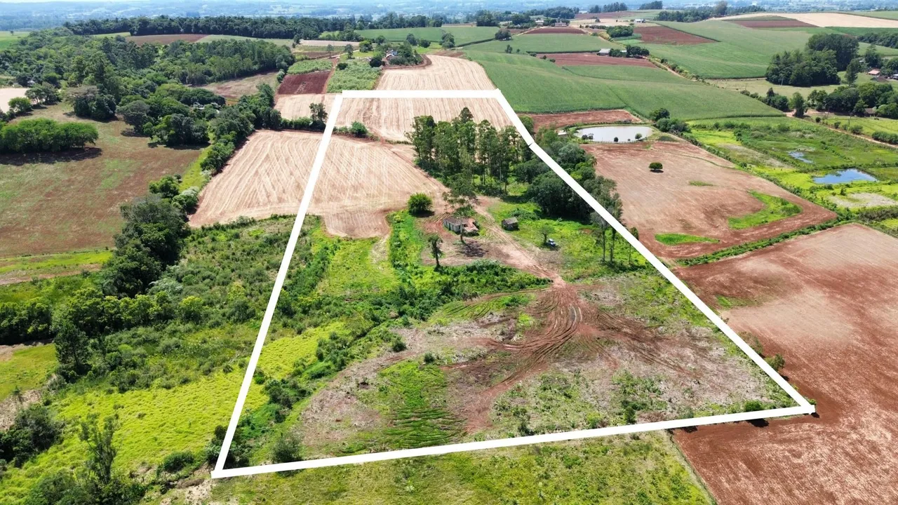 Vista aérea de um terreno rural com áreas de vegetação e campos cultivados em Lajeado.