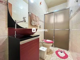 Foto de um banheiro com bancada e box de vidro.