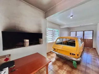Interior de uma sala com lareira e um carro amarelo estacionado.
