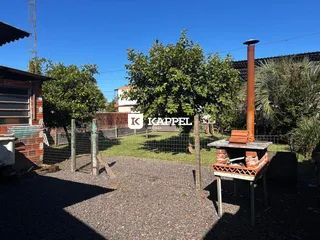 Vista externa mostrando um terreno com cerca e vegetação sob céu azul.