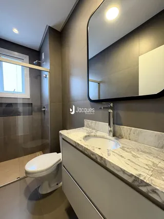 Banheiro moderno com bancada de mármore e box de vidro.