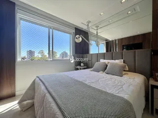 Quarto com grande janela e cabeceira de madeira.