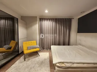 Quarto com cama e poltrona amarela em um imóvel no Brasil.