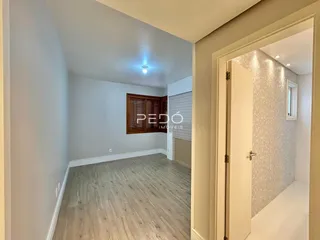 Vista interna de um ambiente com piso de madeira clara e paredes brancas.