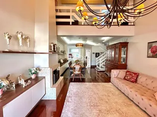 Ambiente interno de uma sala de estar com piso de madeira e escadaria.