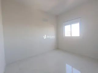 Imagem de um cômodo interno vazio com paredes brancas e piso claro.