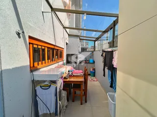 Vista de um corredor com janelas amplas e área de lavanderia exposta.