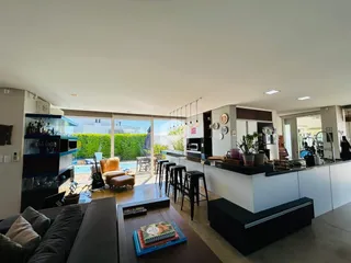Sala de estar com cozinha integrada e acesso a área externa com piscina.