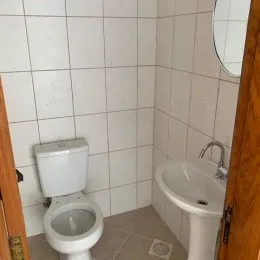 Foto interna de um banheiro com revestimento de azulejos brancos.