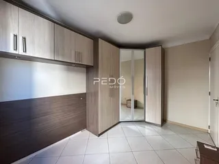 Interior de um cômodo com armários de madeira e piso cerâmico claro.