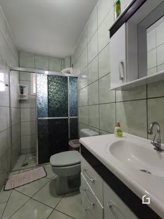Foto de um banheiro com azulejos verdes e vaso sanitário branco.