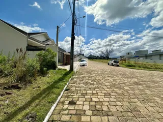 Vista da fachada de uma residência em Lajeado, Brasil, com uma rua pavimentada e vegetação lateral.