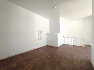 Interior de uma sala com piso de madeira e paredes brancas.