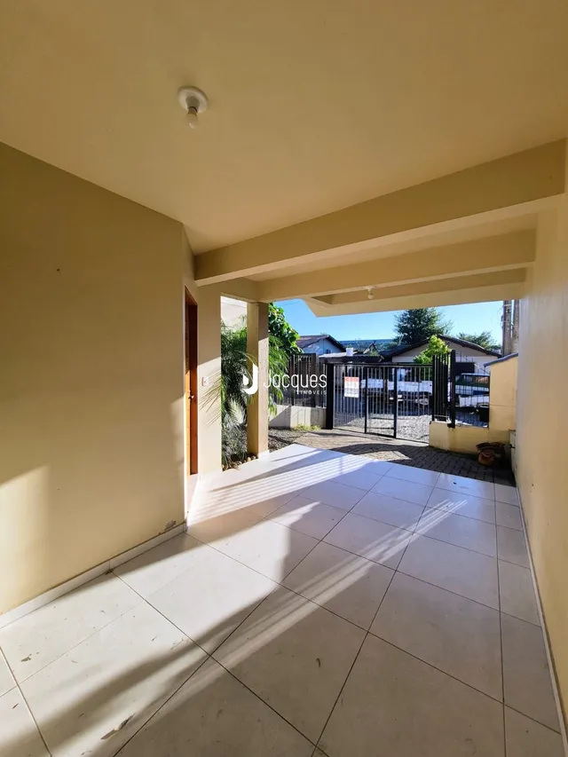 Vista de um espaço interno que se abre para uma área externa pavimentada.