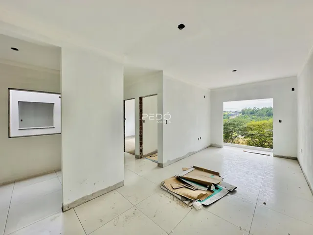 Interior de uma sala com paredes brancas e piso de cerâmica em reforma.