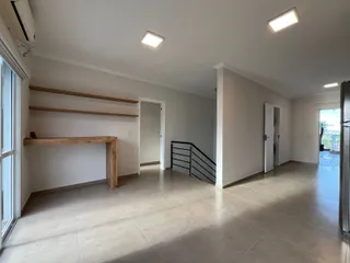 Sala de estar clara com piso de porcelanato e prateleiras de madeira em um imóvel.