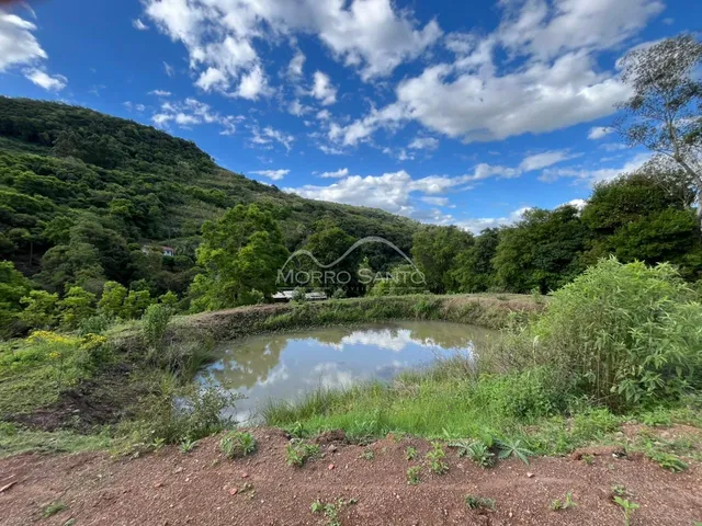 Vista de um lago cercado por vegetação densa e montanhas.