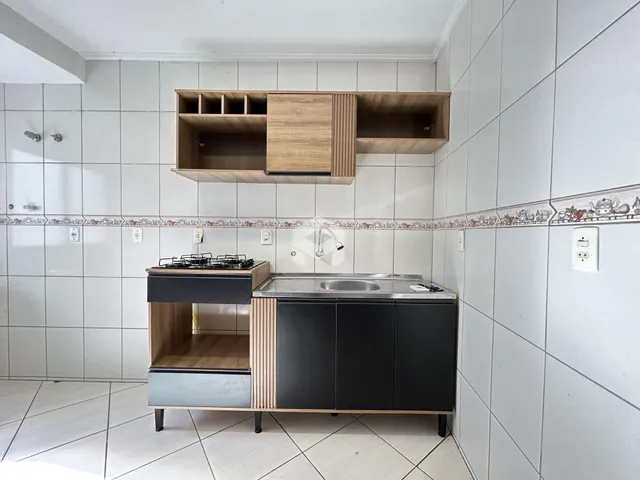 Vista da cozinha com armários de madeira e revestimento branco.
