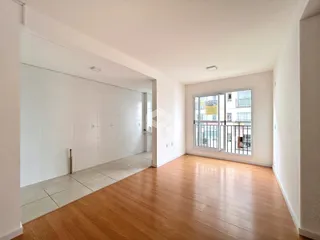 Hall com piso de madeira e paredes brancas em uma residência.