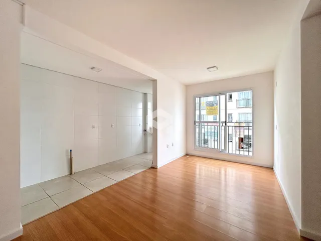 Hall com piso de madeira e paredes brancas em uma residência.