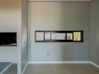 Vista interna de uma sala com paredes cinzas e uma grande janela.