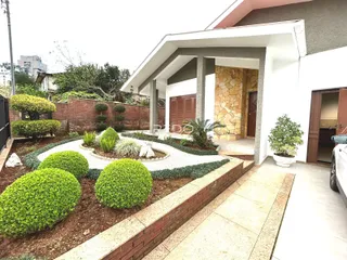 Fachada de uma casa em Lajeado, Brasil com jardim frontal e muro de tijolos.