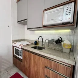 Cozinha com armários de madeira e bancada clara.