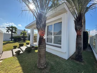 Fachada de uma casa branca com palmeiras no jardim.