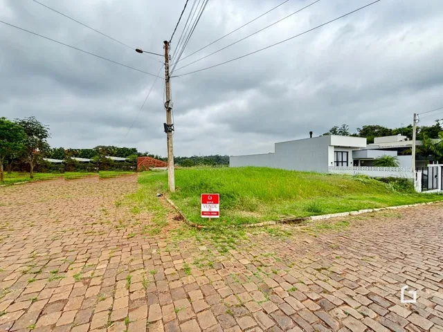 Vista externa de uma propriedade com terreno gramado e calçada de tijolos.