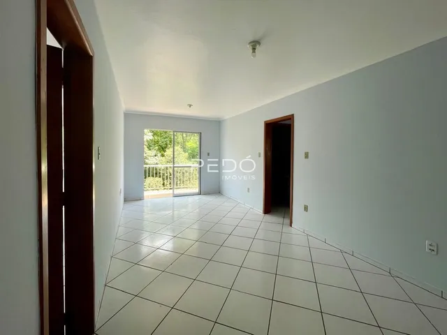 Corredor interno de um imóvel com piso de cerâmica e portas de madeira.