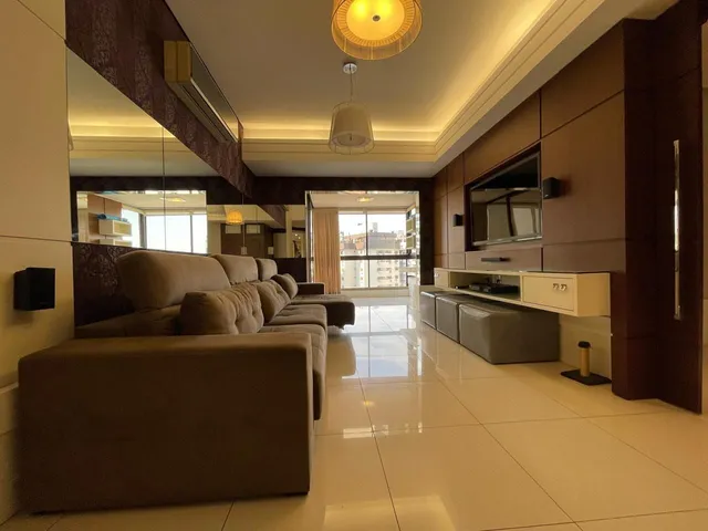 Sala de estar com sofá grande e piso de porcelanato claro.