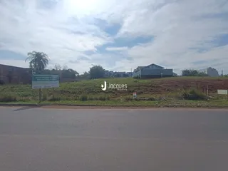 Vista externa de uma propriedade com vegetação e uma estrada no primeiro plano.