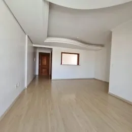 Sala de estar ampla com piso de madeira clara e paredes brancas.