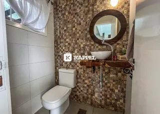 Foto de um banheiro com revestimento de azulejos marrons e um espelho redondo.