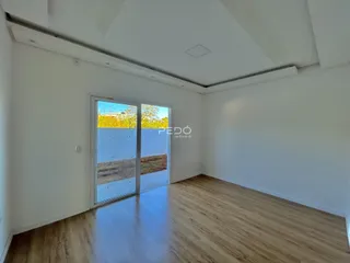 Ambiente interno com piso de madeira e porta de vidro que dá para o exterior.