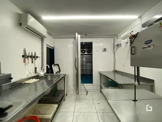 Interior de uma cozinha com bancadas de aço inoxidável.