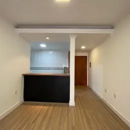 Hall de entrada com piso de madeira clara e paredes brancas.