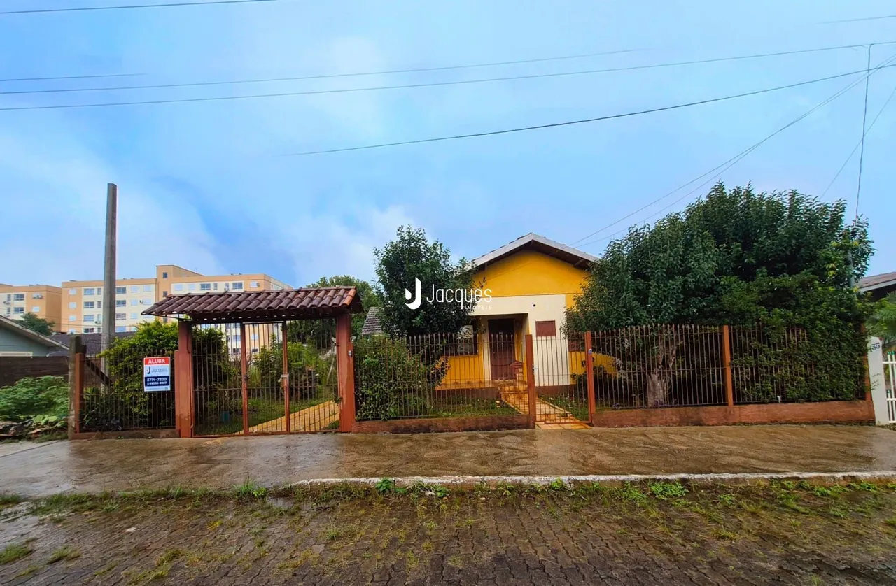 Fachada de uma residência em Lajeado, Brasil, com portão de madeira e cerca.