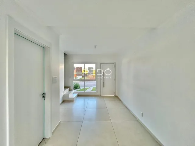 Hall de uma propriedade com paredes brancas e piso de cerâmica claro.