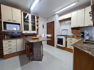 Cozinha com armários brancos e bancadas de granito.