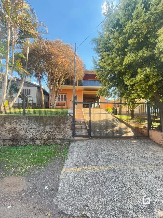 Vista da fachada de uma propriedade em Lajeado, Brasil, com cerca e portão de ferro.
