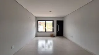 Vista interna de um corredor longo com piso claro e uma janela.