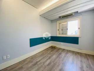 Vista interna de um cômodo com paredes brancas e piso de madeira clara.